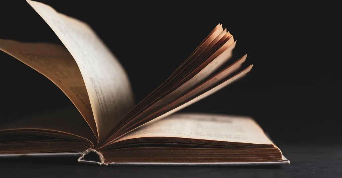 Un gros plan artistique d'un livre ouvert avec des pages tournantes sur un fond noir.