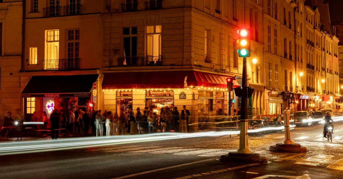 Photo à longue exposition capturant l'animation nocturne et les lumières vibrantes d'un carrefour parisien.