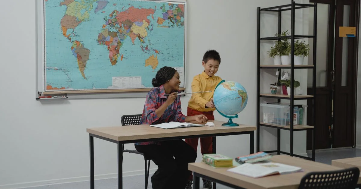 Un enseignant et un étudiant regardant un globe dans une salle de classe moderne, avec une carte du monde sur le mur.