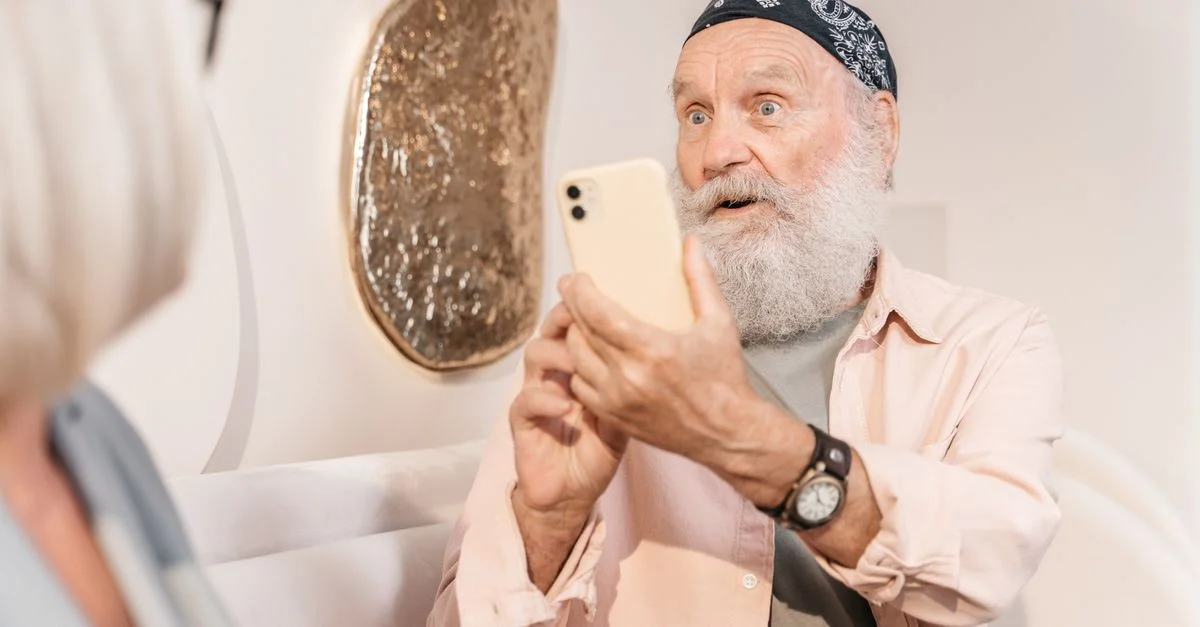 Un homme senior avec un smartphone dans un cadre moderne, exprimant la surprise.