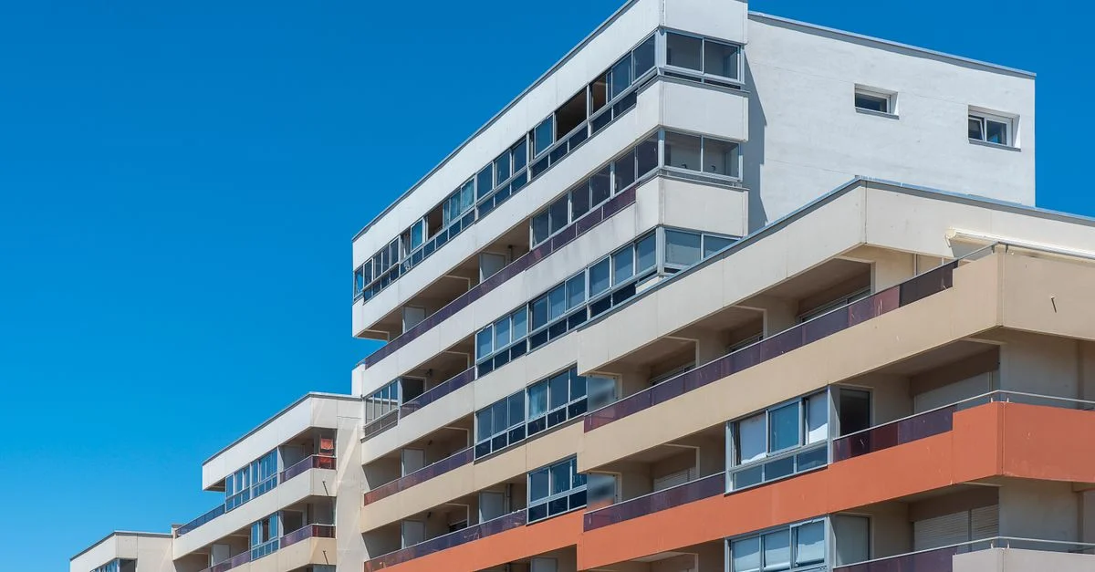 Immeubles d'appartements contemporains à plusieurs étages avec balcons sous un ciel bleu azur, illustrant une architecture moderne.