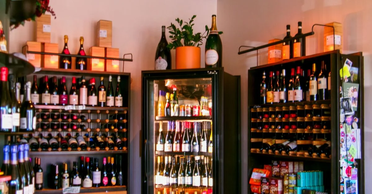 Intérieur coloré d'une cave à vin présentant un assortiment de bouteilles de vin sur des étagères.